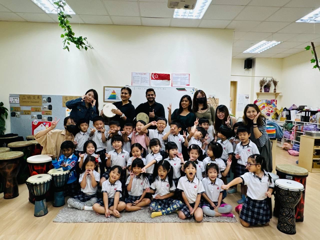 A large group of young students and teachers posing together after a World Percussion session