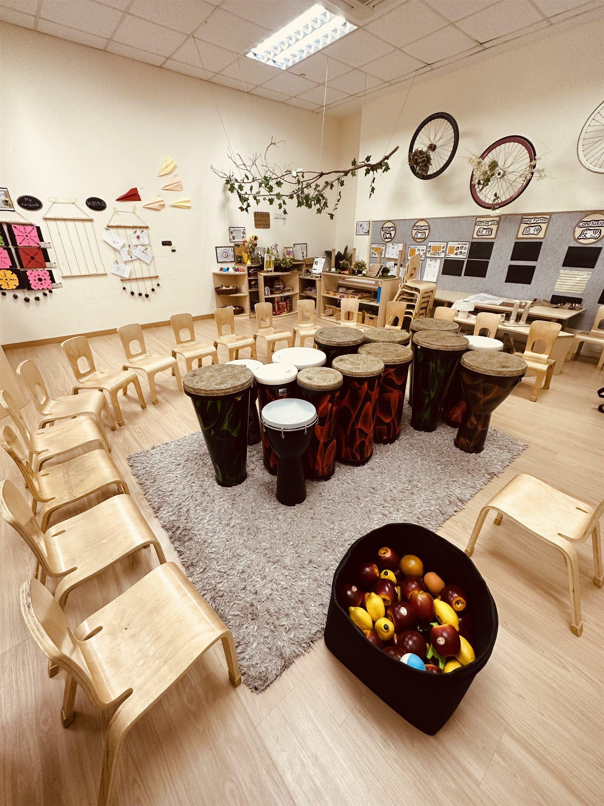 A classroom set up with djembe drums arranged in a circle on a rug for a World Percussion session