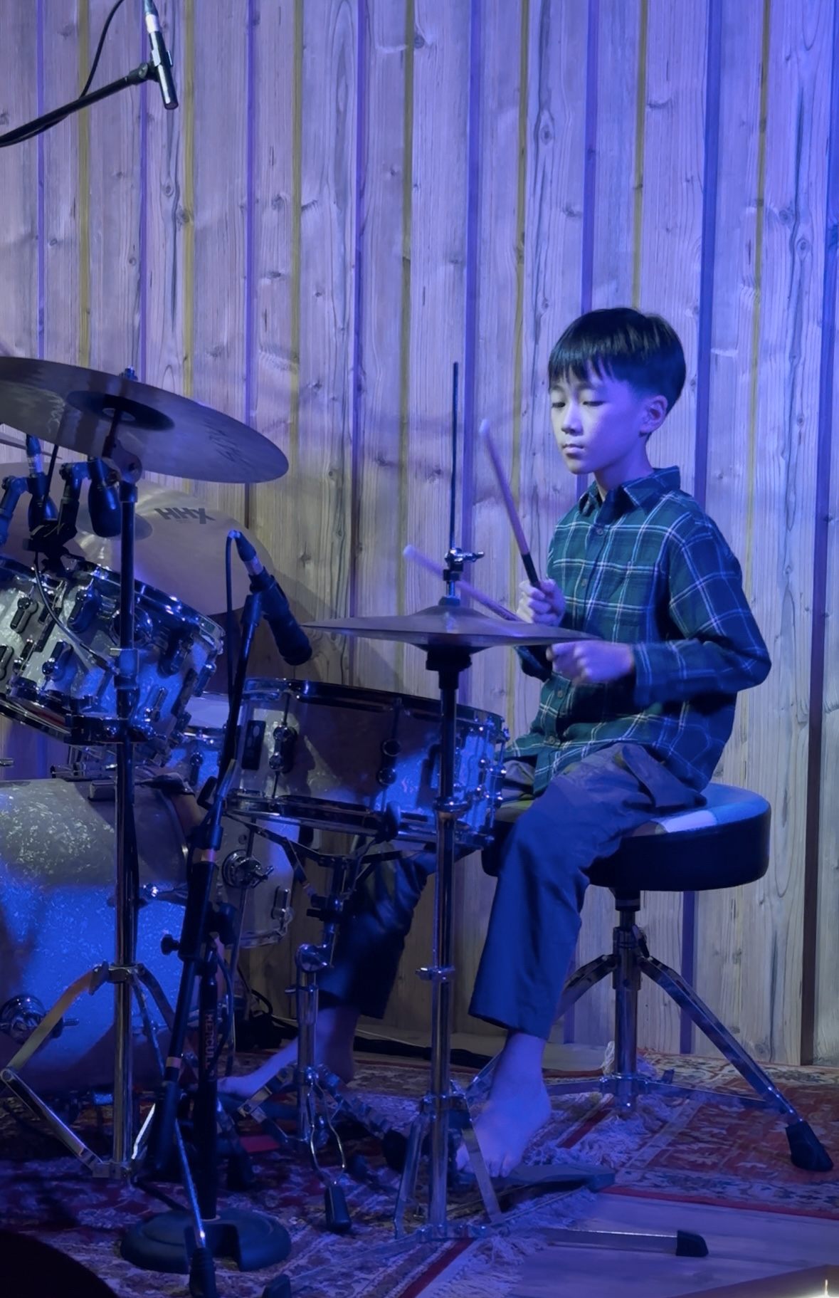 Student playing a drum kit under stage lighting at Drum Prodigy