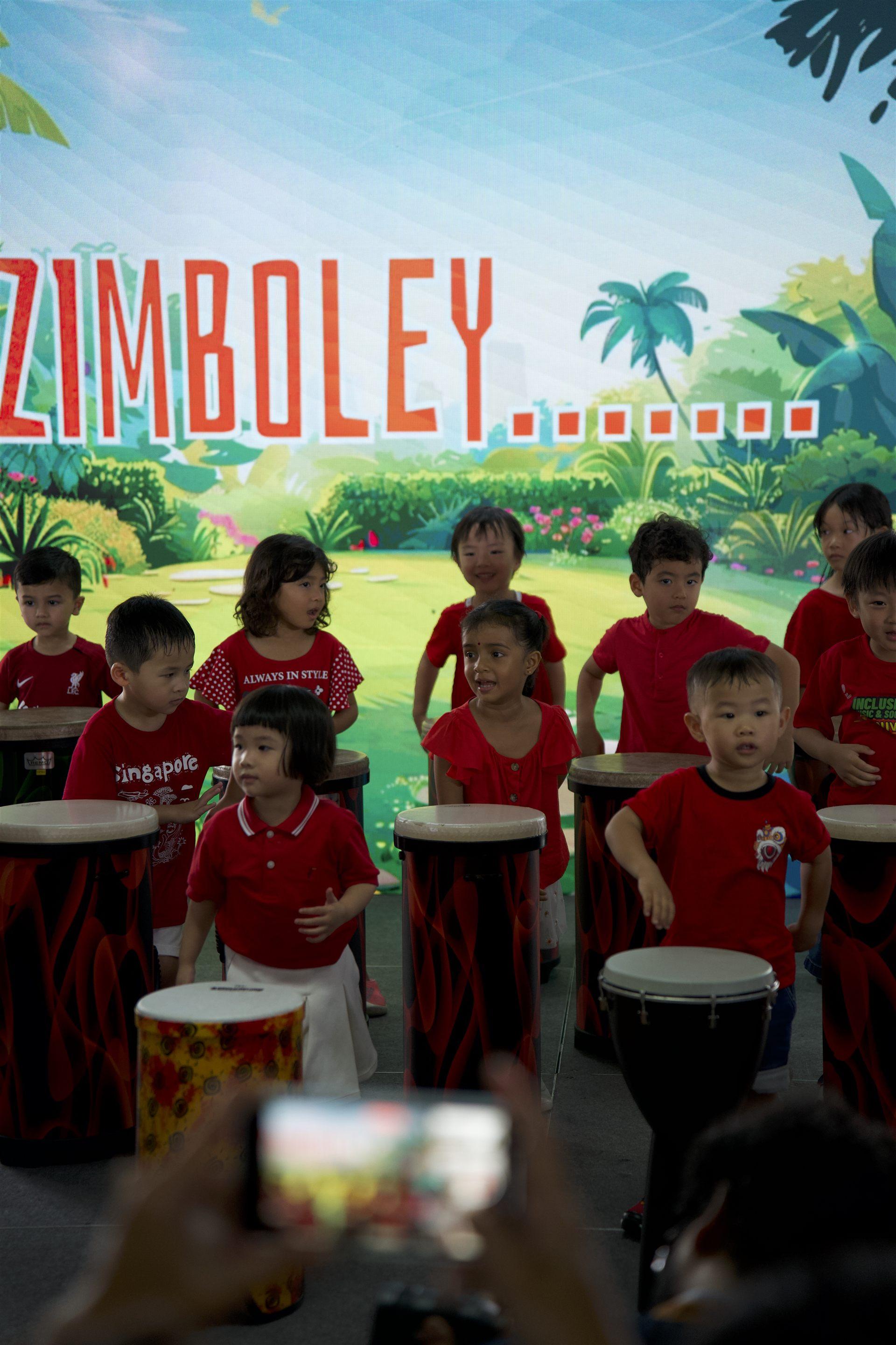 Children performing on djembe drums on stage at the carnival